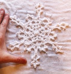 a person's hand on top of a piece of crochet