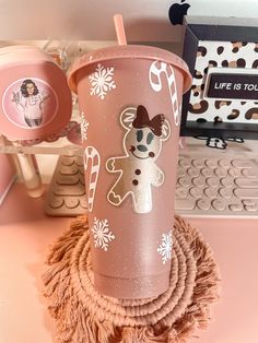 a pink cup sitting on top of a table next to a computer keyboard and mouse