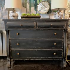 a black dresser with two lamps on top of it