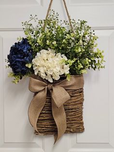 a basket hanging on the door with flowers in it and a ribbon tied around it