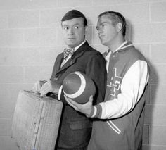 two men standing next to each other with luggage in front of them and one holding a ball