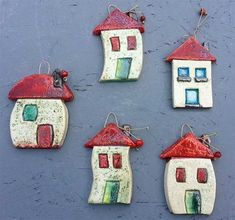 four ceramic houses hanging from hooks on a wall