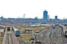 there are many trains that are on the tracks in this city area, and one train is coming down the track