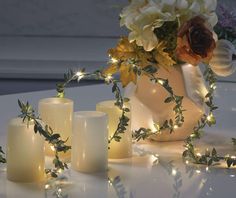 some candles are sitting on a table with flowers