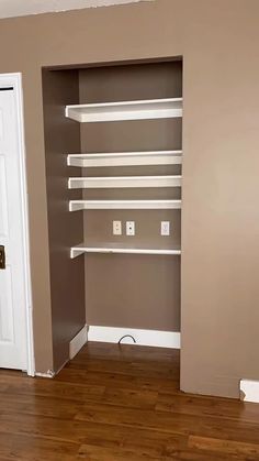 an empty closet with shelves in the corner and a door to another room behind it