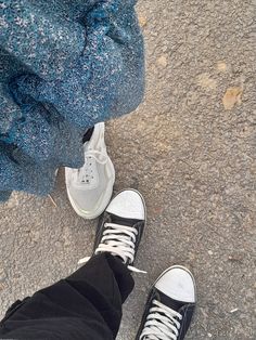 two people standing on the ground with their feet up and one person wearing black and white sneakers