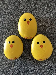 three yellow painted rocks with black eyes on them