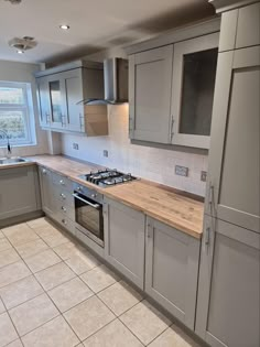 a kitchen with grey cabinets and wooden counter tops in the middle of tile flooring