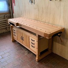 a wooden workbench sitting on top of a brick floor next to a wall