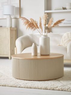 a living room with a white couch and some plants in a vase on the coffee table