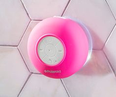 a pink speaker sitting on top of a white tile floor next to a tiled wall