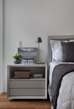 a bedroom with a bed, night stand and lamp on the side table next to it