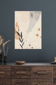 an abstract painting hangs on the wall above a dresser with two vases and plants