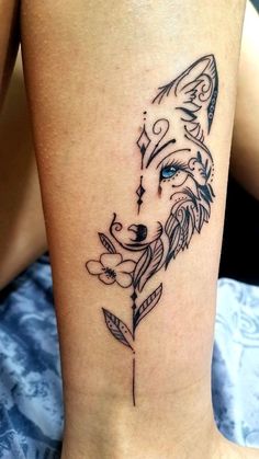 a tattoo on the leg of a woman with a wolf's head and leaves