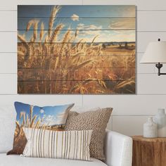 a living room scene with focus on the couch and wall art that has wheat stalks in it