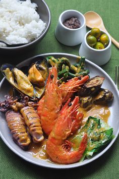 a plate with shrimp, mussels and other foods on it next to bowls of rice