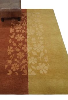 a brown and tan rug with flowers on the floor next to a chair in front of it