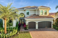 a large house with palm trees in front of it and landscaping around the driveway area