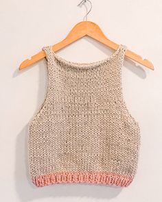 a knitted top hanging on a wooden hanger