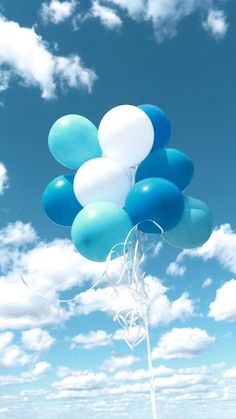 a bunch of blue and white balloons floating in the air