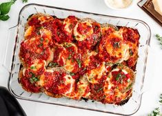 a glass casserole dish filled with meatballs and sauce on top of a white table