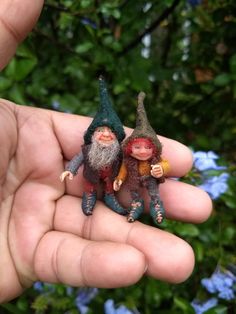 two miniature gnomes sitting on top of each other in the palm of someone's hand