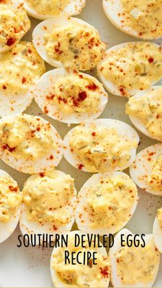 deviled eggs on a white plate with seasoning sprinkled around them, ready to be eaten