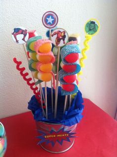 a bucket filled with cake pops and captain america lollipops on top of a table