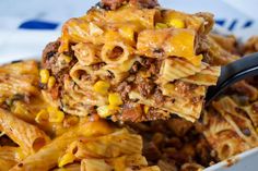 a spoon full of pasta and meat casserole with corn on top is being held up by a fork