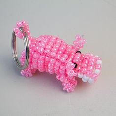 a pink beaded animal ring sitting on top of a white table next to a pair of scissors