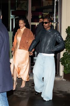 a man and woman holding hands as they walk out of a building with other people