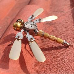 a small metal propeller on top of a red cloth with two gold balls attached to it