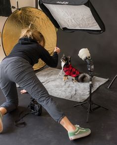 a woman kneeling down in front of a camera with a dog on the ground next to her