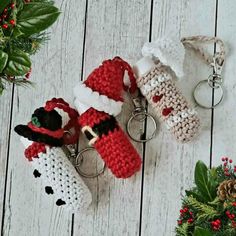 three crocheted keychains with santa claus and snowman on them sitting next to holly wreaths