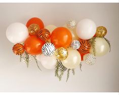 an arrangement of balloons with gold, white and orange decorations