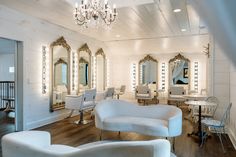 a salon with white chairs and chandeliers