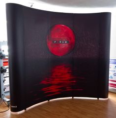 a curved display in the middle of a wood floored area with red paint on it