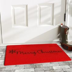 a red door mat with the words merry christmas written on it next to a pair of rubber boots