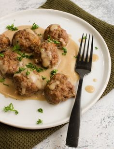 meatballs covered in gravy on a plate with a fork