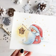 a hand holding up a card with an image of santa clause on it, surrounded by christmas decorations