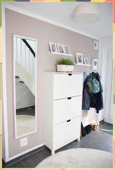 a white dresser sitting next to a mirror on top of a wooden floor in a room