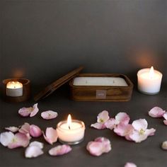 candles and flowers on a table next to a wooden box with a candle in it