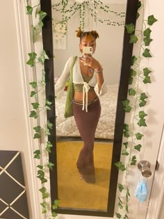 a woman taking a selfie in front of a mirror with ivy growing on it