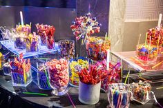 there are many candy bars and candies on display in the glass vases with colorful sticks sticking out of them