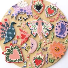 an assortment of decorative magnets are arranged on a circular surface with flowers, hearts, and birds