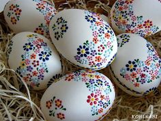 six decorated eggs in a box with straw on the bottom and flowers painted on them