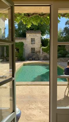 a person sitting at a table in front of a pool with an open patio door