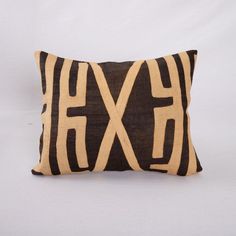 a brown and black pillow with an x on the front, sitting on a white background