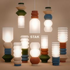 a group of different colored lamps hanging from strings with the words stak above them