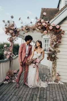 a man and woman standing on a porch holding hands